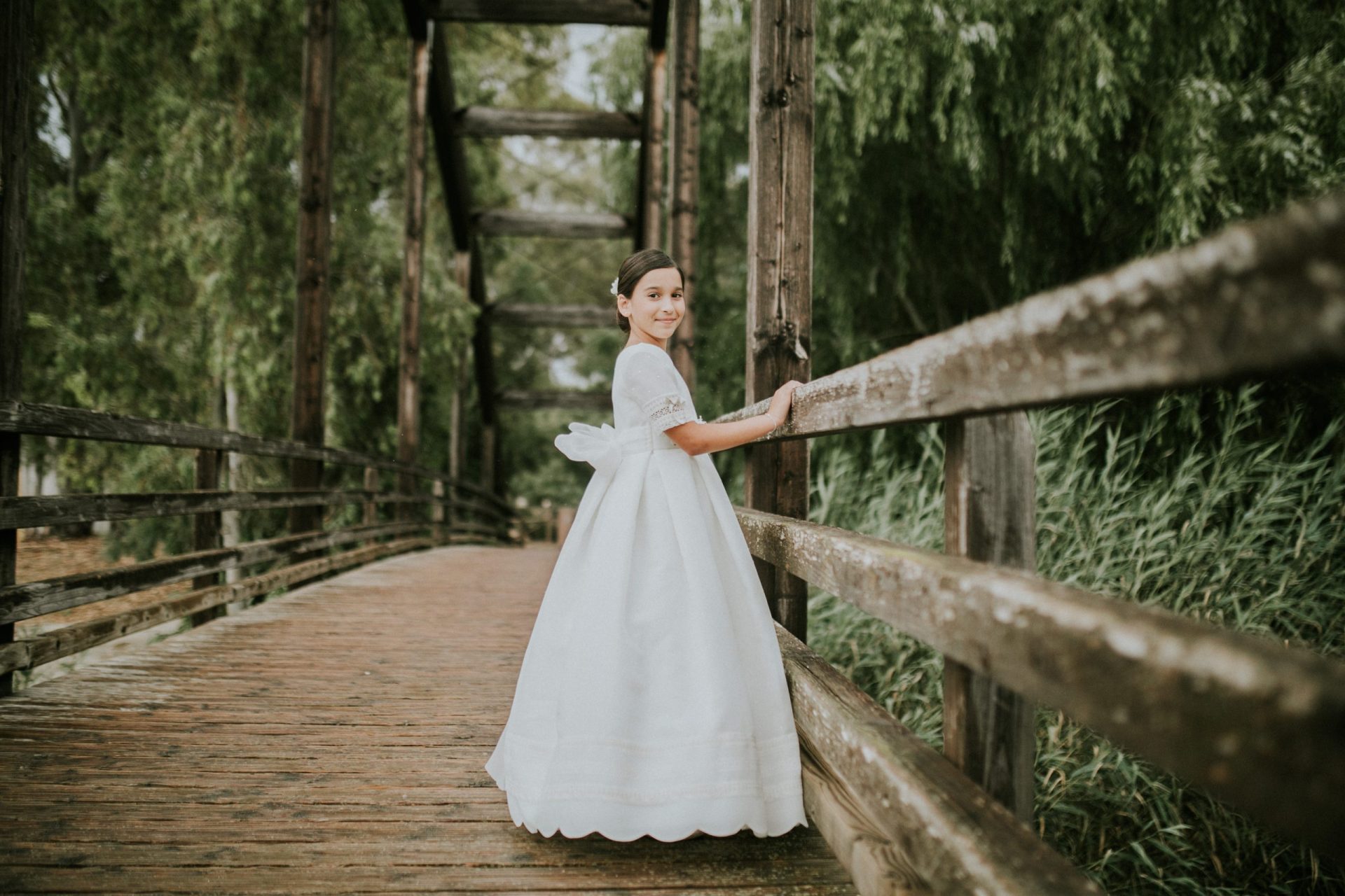 Niña con vestido de comunión en un puente