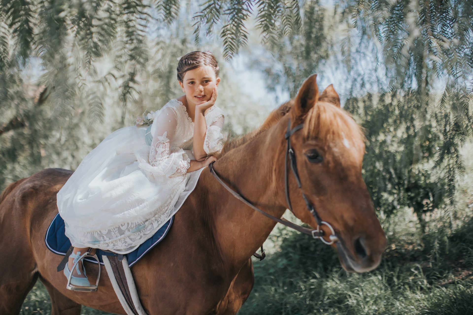 Niña con vestido de comunión sobre un caballo