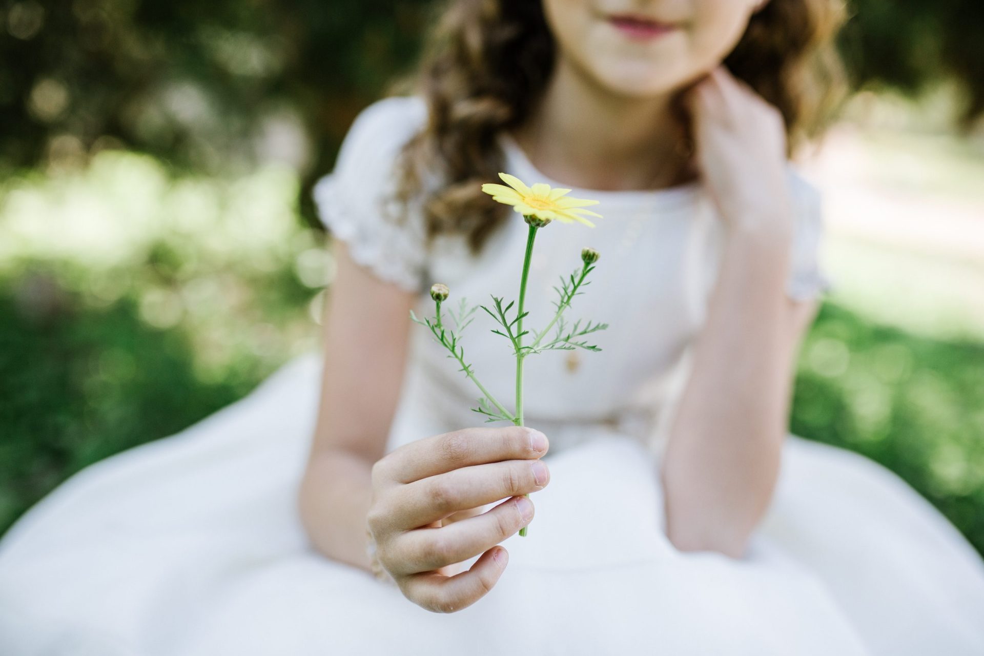 Niña con vestido de comunión y con una flor en la mano