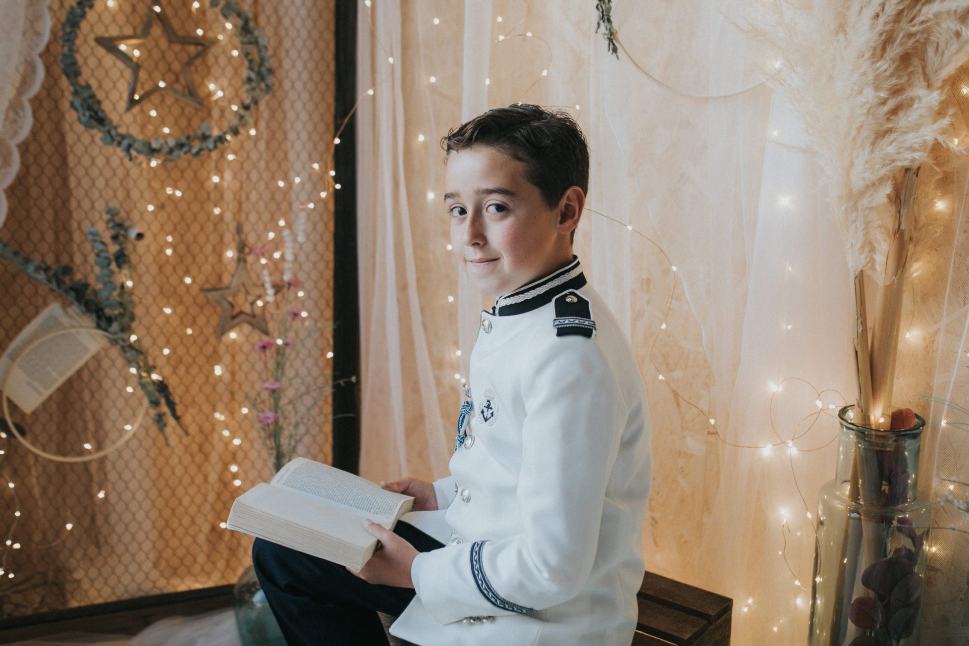 Niño sonriente con su traje de comunión y un libro