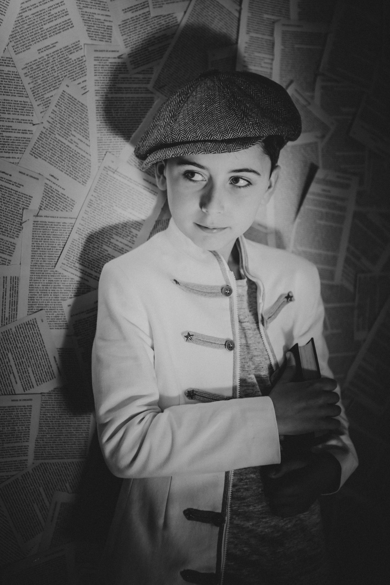 Fotografía de un niño en blanco y negro con un fondo de papeles