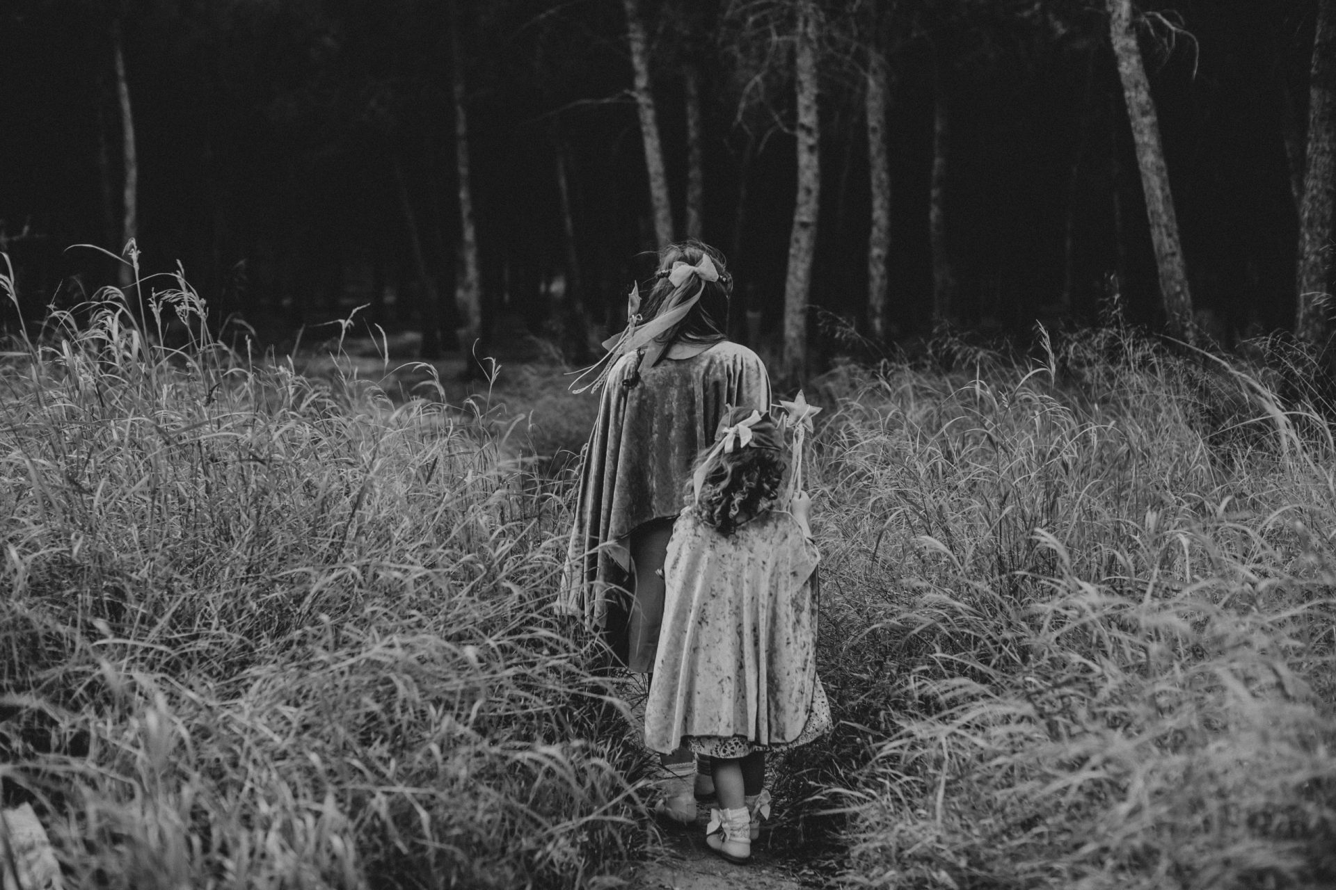 Fotografía en blanco y negro de unas niñas disfrazadas de hadas madrinas en el campo