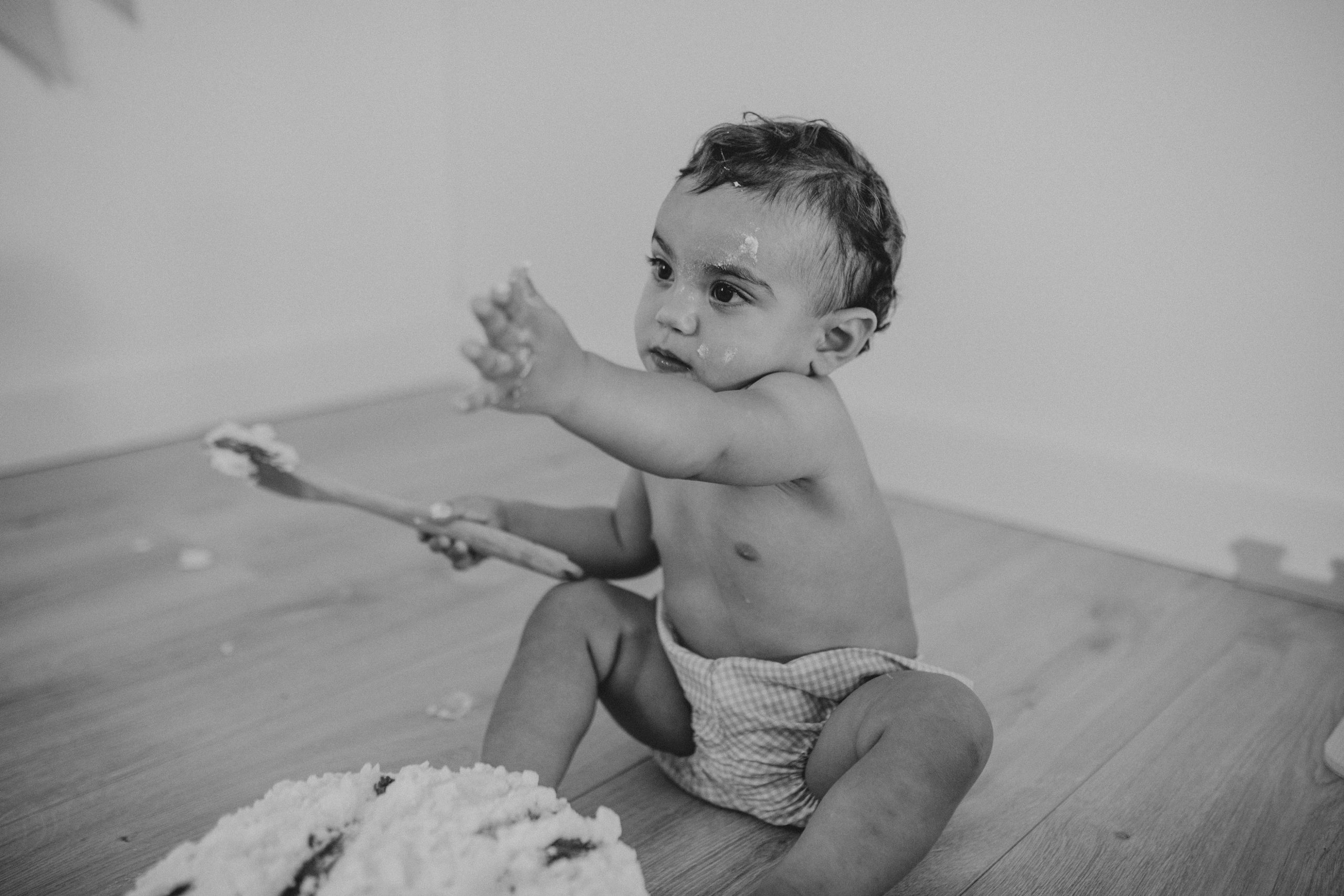 Fotografía en blanco y negro de un niño ensuciándose con la tarta