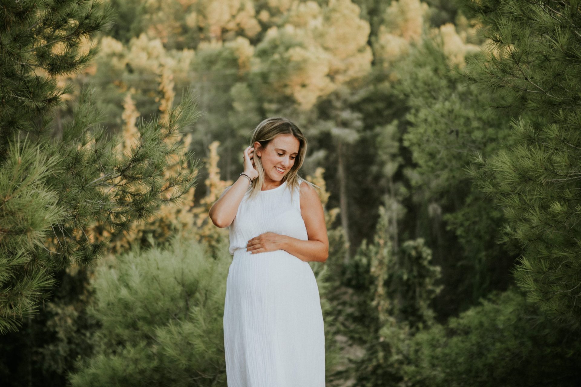 Mujer embarazada sonriendo en medio del bosque