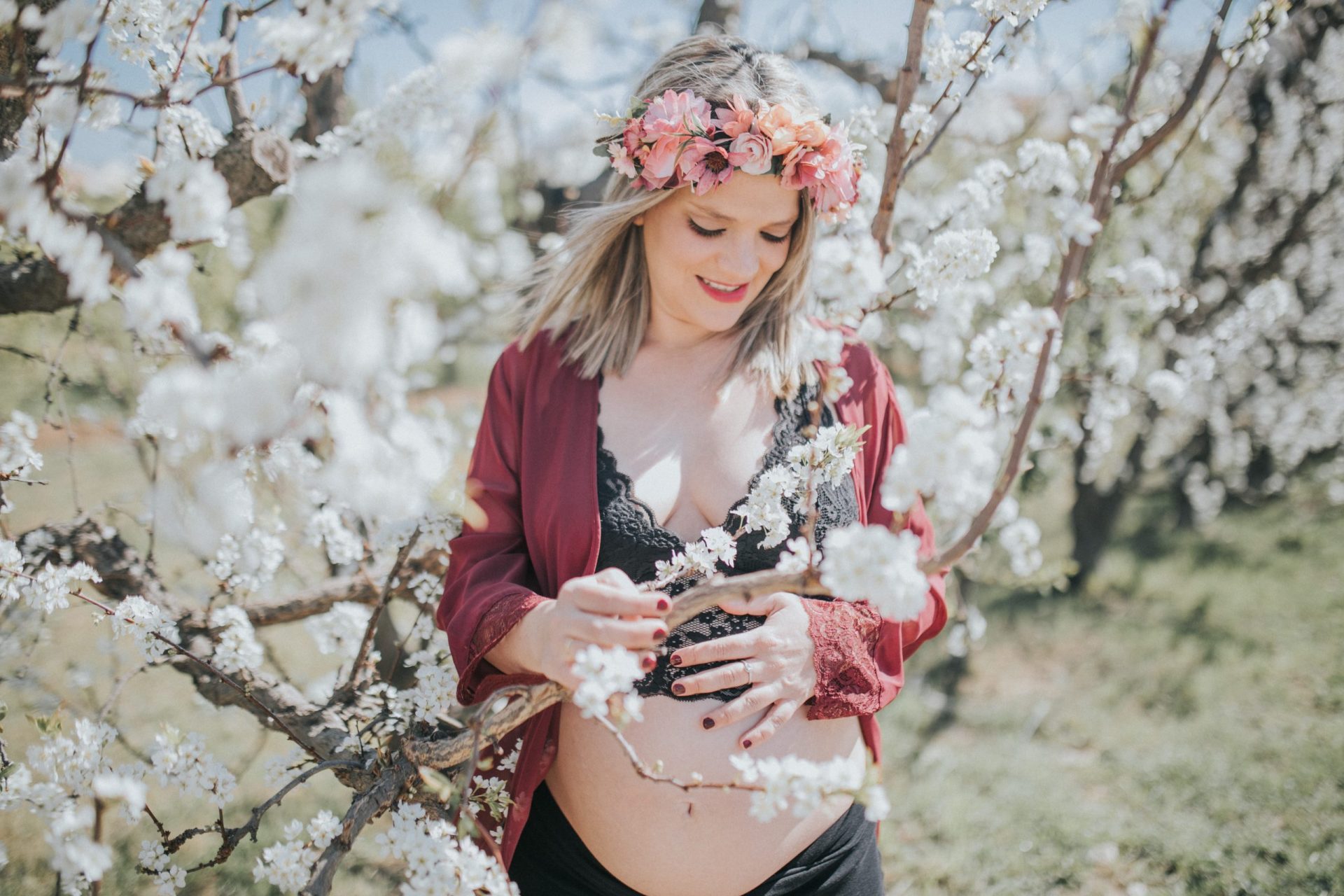 Mujer embarazada cogiendo una rama de cerezos