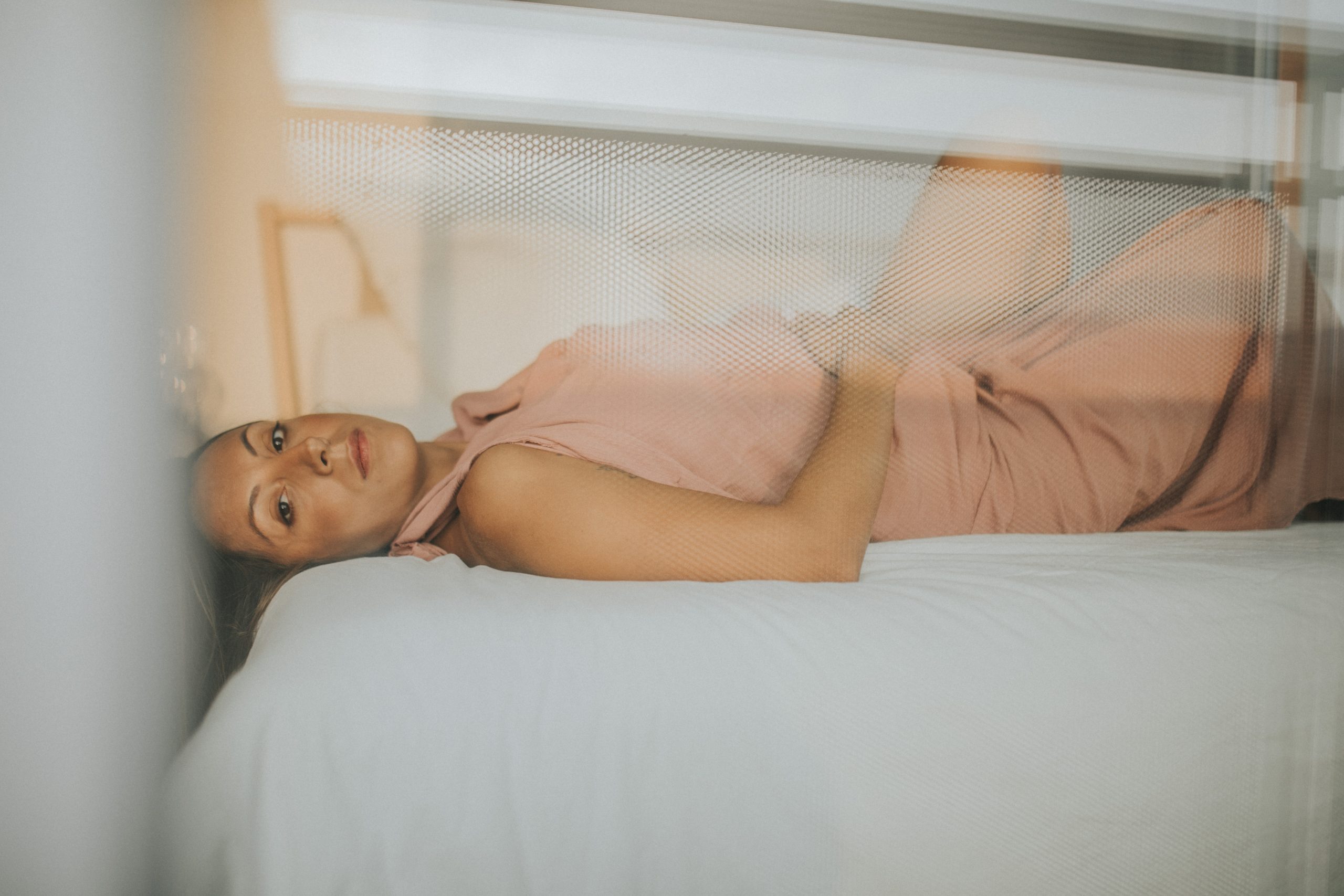Mujer sobre una cama acariciando su barriga de embarazada