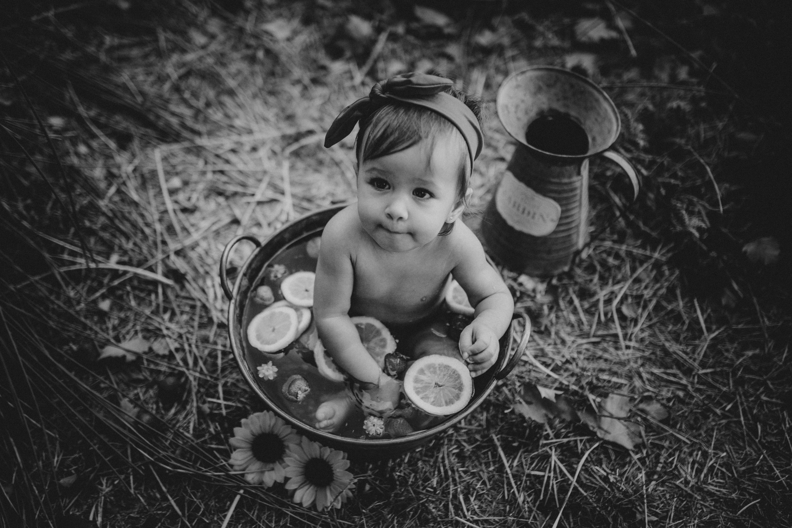 Fotografía en blanco y negro de una niña en un cubo lleno de agua