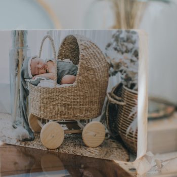 Fotografía impresa de un niño dormido sobre un carrito de paja trenzada