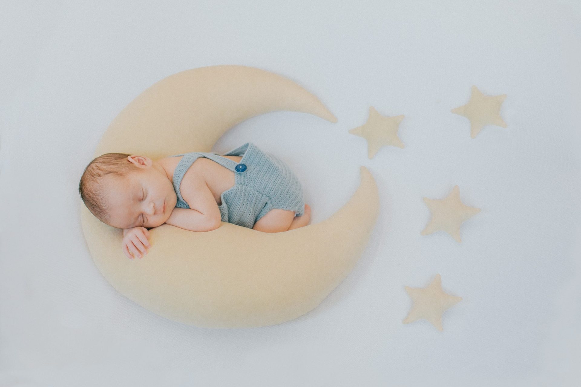 Bebé dormido sobre un almohada en forma de luna