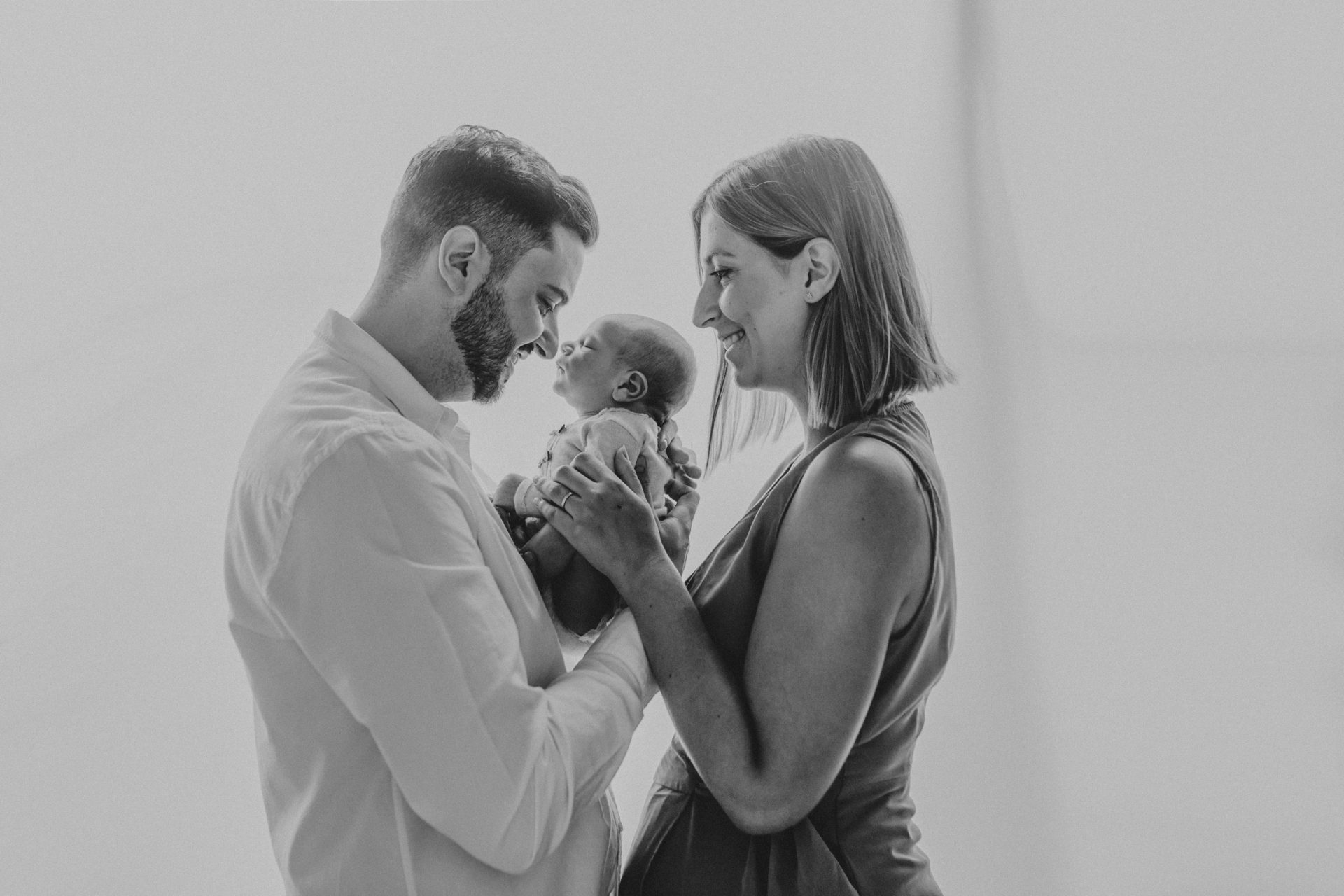 Imagen en blanco y negro de padre y madre sujetando a su recién nacido