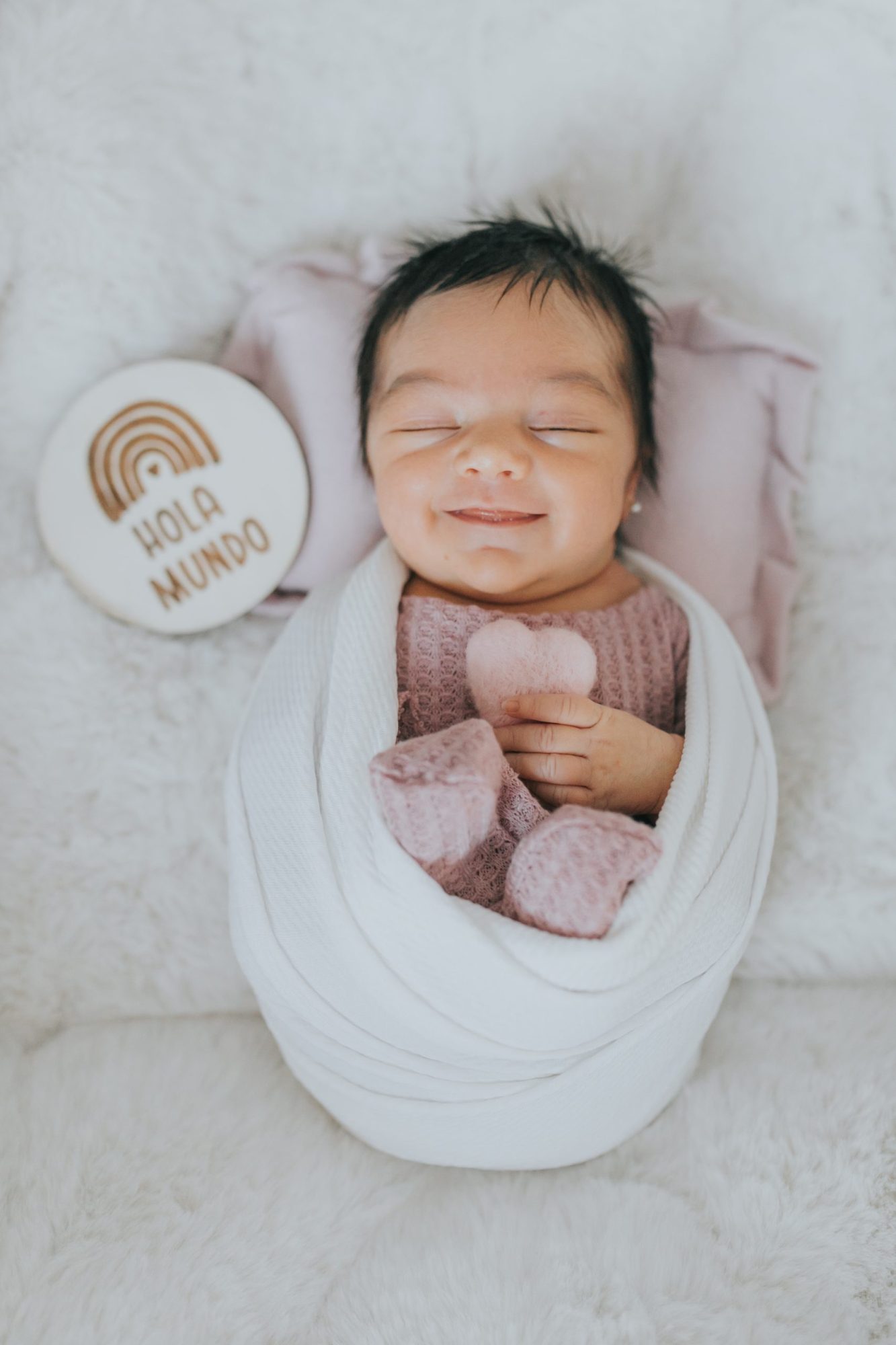 Bebé sonriente con los ojos cerrados y envuelta en mantas
