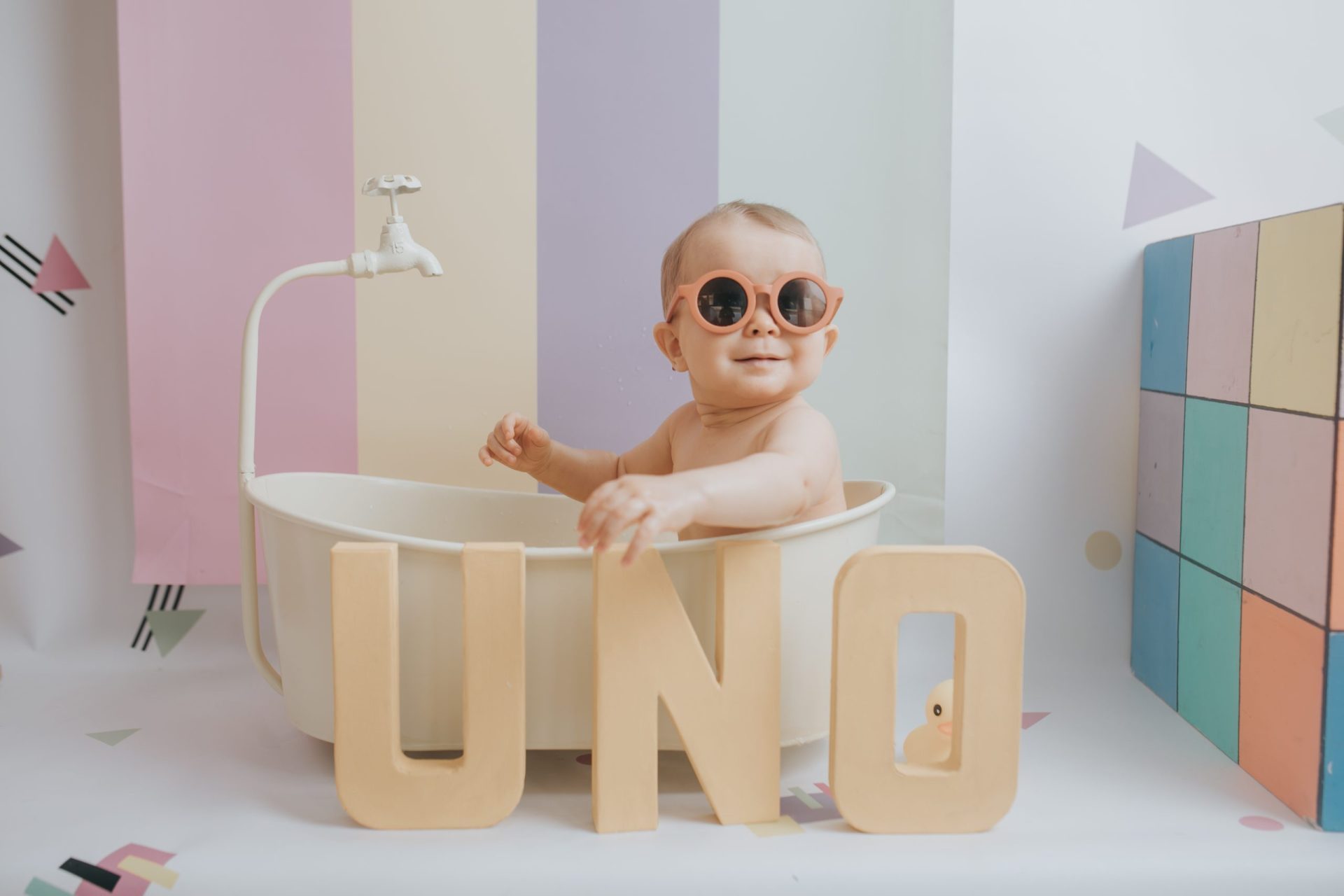 Bebé con gafas de sol dentro de una bañera de juguete