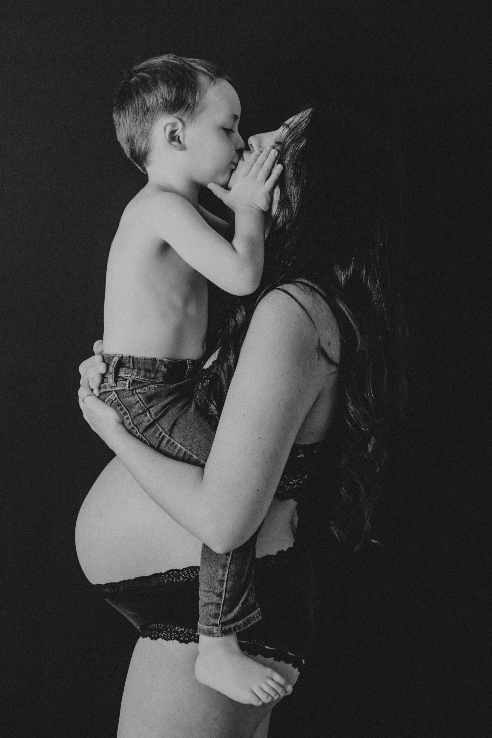 Fotografía en blanco y negro de una madre dandole un beso a su hijo